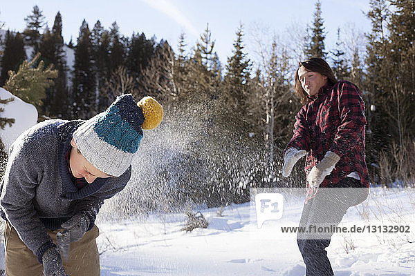 Teenagers playing with snow on sunny day