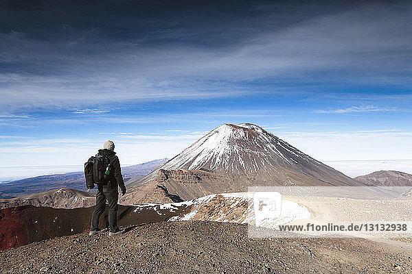 Rückansicht eines Wanderers  der den Mt. Ngauruhoe vor bewölktem Himmel betrachtet