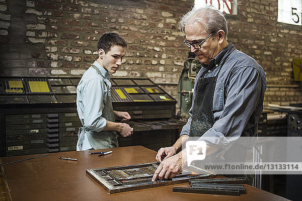 Arbeiter ordnet Buchdruckausrüstung auf der Werkbank in der Werkstatt an