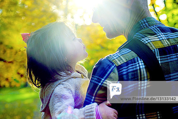 Nahaufnahme eines Großvaters und einer Enkelin  die sich an einem sonnigen Tag im Park anschauen