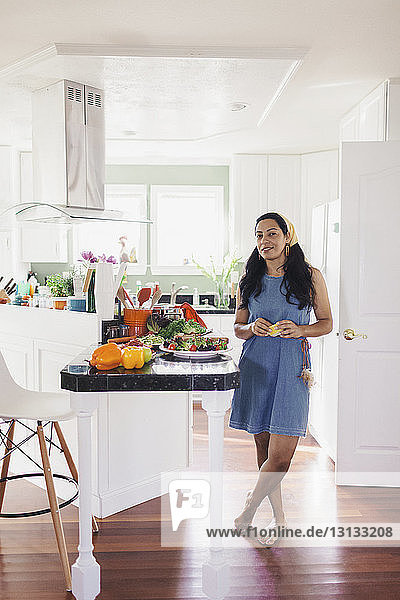 Ganzflächiges Porträt einer selbstbewussten Frau  die auf einem Hartholzboden in der Küche steht