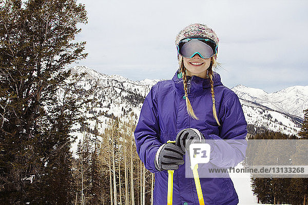 Lächelnde Frau steht vor schneebedeckten Bergen
