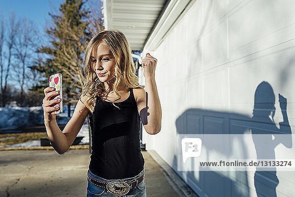 Girl taking selfie while standing by house