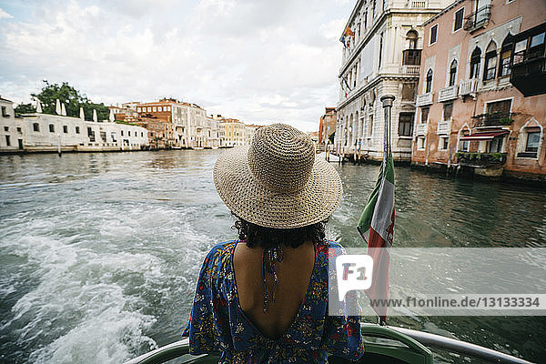 Rückansicht einer Frau  die im Boot über den Kanal in der Stadt fährt