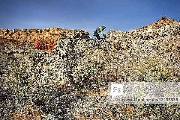 Side view of hiker mountain biking at desert