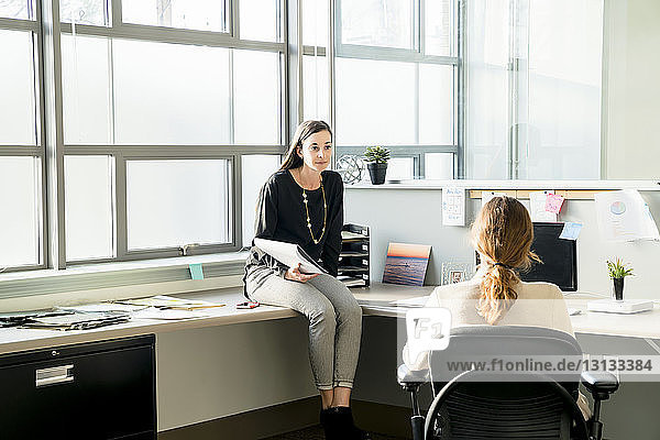 Businesswomen talking while sitting in office
