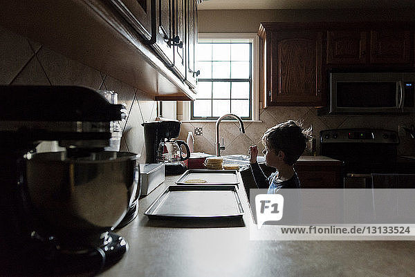 Junge schaut Waffel auf Tablett an  während er in der Küche steht