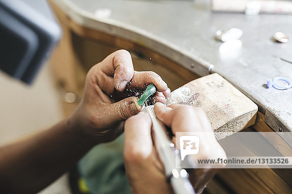 Geschnittene Hände Künstlerin formt Ring mit Ausrüstung auf Tisch in Werkstatt
