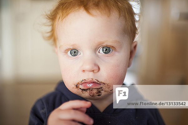 Portrait eines traurigen kleinen Jungen  dem zu Hause Essen um den Mund herumgeworfen wird