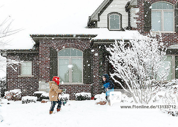 Glückliche Brüder spielen mit Schnee im Hof