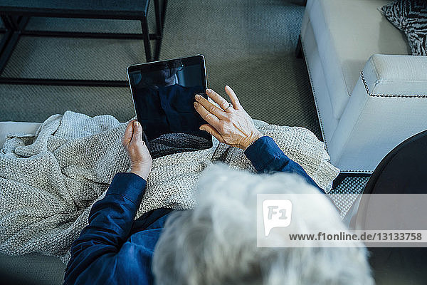 Hochwinkelansicht einer älteren Frau  die zu Hause einen Tablet-Computer benutzt