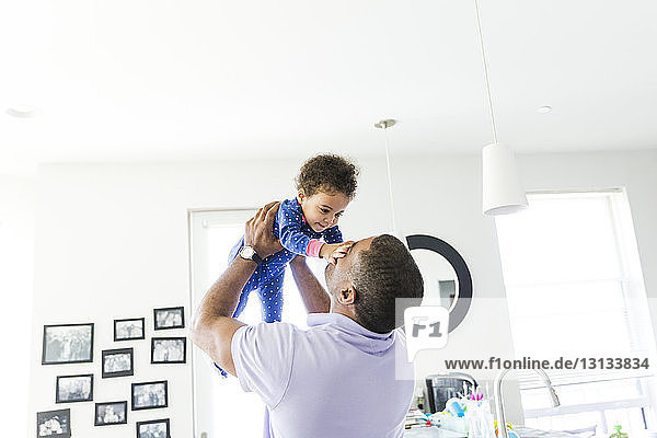 Father lifting daughter while standing at home
