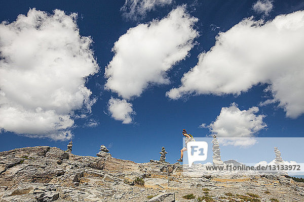 Low angle view of female hiker walking on rock formations against cloudy sky at North Cascades National Park