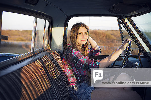 Portrait of woman with hand on steering wheel in pick-up truck