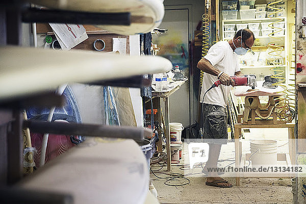 Seitenansicht eines Handwerkers  der in der Werkstatt ein Surfbrett herstellt