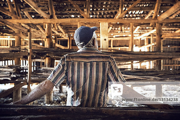 Rückansicht eines Mannes  der in einem unvollständigen Holzgebäude steht