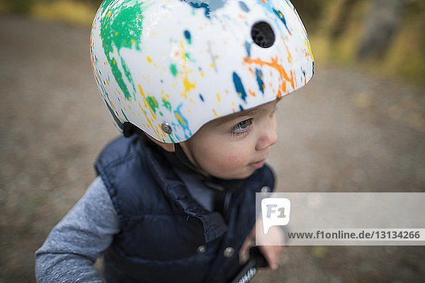 Cute baby boy wearing bicycle helmet while looking away