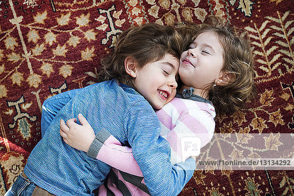 Süße Geschwister umarmen sich  während sie zu Hause auf dem Boden liegen