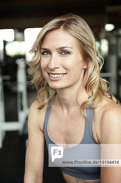 Portrait of smiling sportswoman sitting in gym