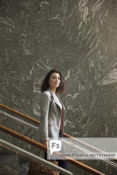 Thoughtful businesswoman standing on steps in modern building