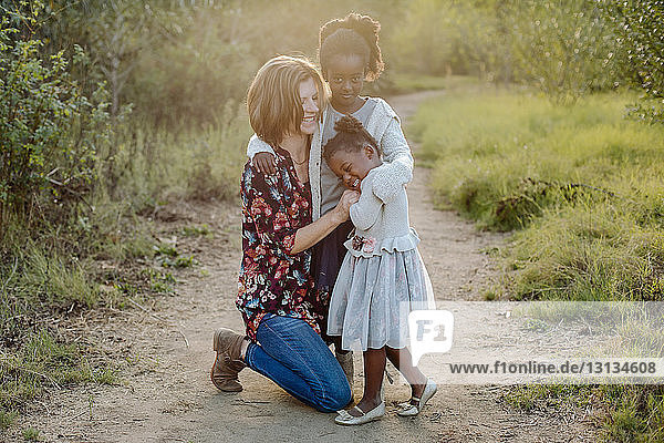 Mutter mit Töchtern auf Wanderung inmitten eines Feldes im Park