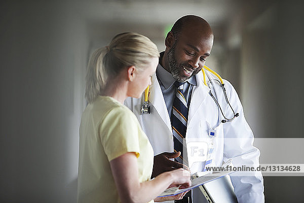 Male doctor checking papers with nurse at hospital