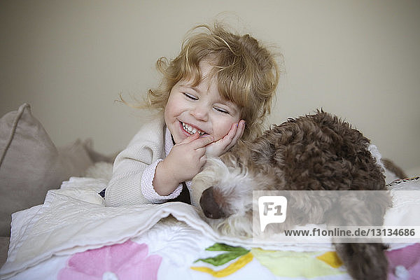 Happy girl relaxing with dog on bed at home