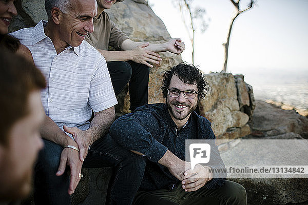 Glückliche Söhne im Gespräch mit den Eltern  während sie im Park bei Felsformationen sitzen