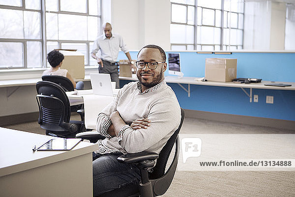 Portrait of confident businessman with colleagues in background at office
