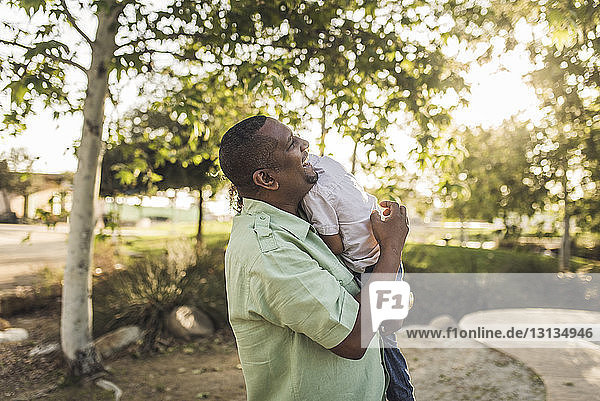 Glücklicher Vater umarmt Sohn  während er im Park steht