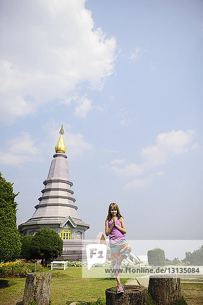 Girl standing in tree pose against pagoda at Doi Inthanon National Park