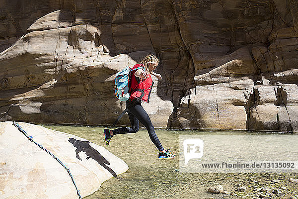 Female backpacker jumping in water on sunny day