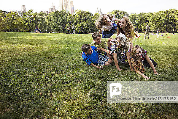 Children enjoying with mother on grassy field at park