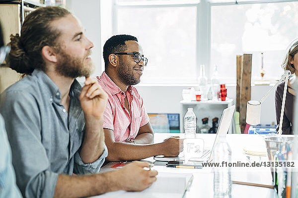Business people looking away while sitting at table in meeting