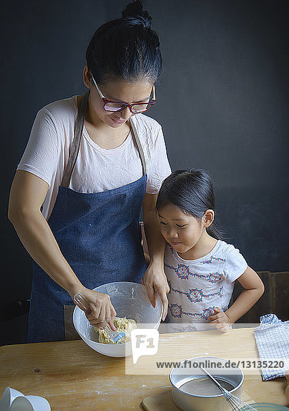 Mutter bringt Tochter bei  Teig in der Küche in einer Schüssel zu mischen