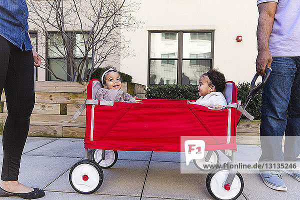 Niedriger Anteil von Eltern  die bei Töchtern stehen  die im Kinderwagen auf dem Fußweg sitzen