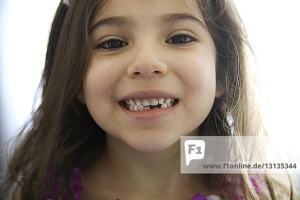Close-up portrait of girl with gap toothed at home