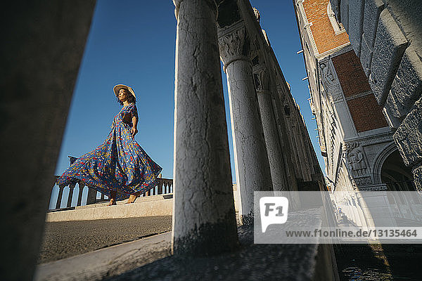 Niedrigwinkelansicht einer Frau auf einer Brücke durch ein Geländer in der Stadt gesehen