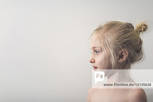 Side view of cute shirtless girl standing against wall at home