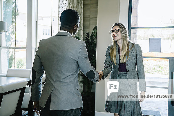 Geschäftsleute schütteln sich die Hand  während sie im Büro an der Tür stehen