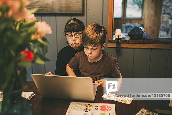 Enkel bringt Großmutter bei  zu Hause einen Laptop auf dem Tisch zu benutzen