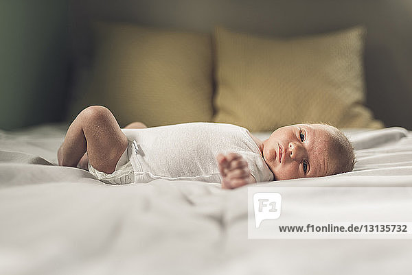 Portrait of newborn baby boy lying on bed at home