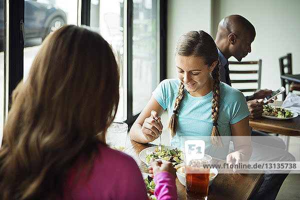 Mother with daughter having food in restaurant