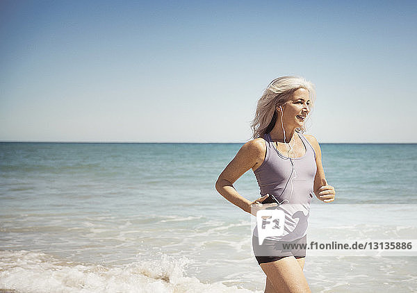 Volle Länge einer fitten Frau  die am Delray-Strand an der Meeresküste läuft