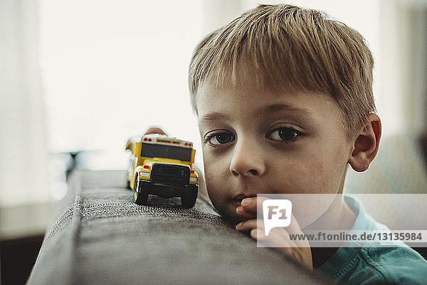 Porträt eines Jungen  der zu Hause mit einem Spielzeuglastwagen spielt