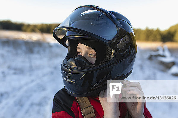Nahaufnahme eines Teenagers mit Helm auf schneebedecktem Feld gegen den Himmel