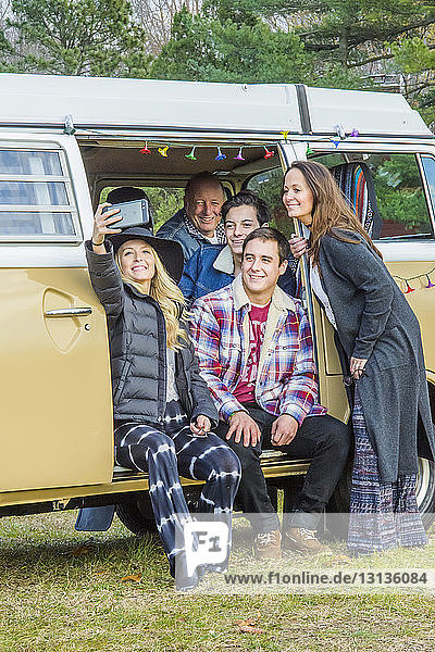 Happy family taking selfie at doorway of van