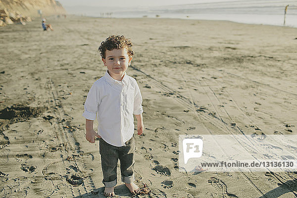 High angle portrait of cute boy standing at beach during sunny day