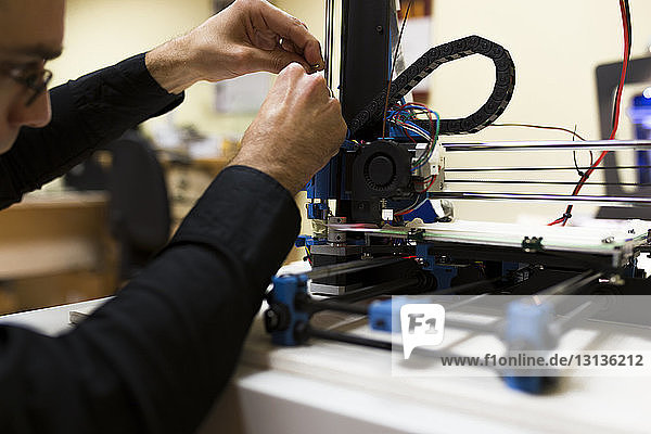Männlicher Ingenieur fixiert 3D-Drucker auf Tisch