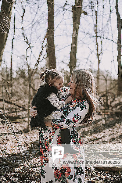 Schwangere Mutter trägt Tochter im Wald